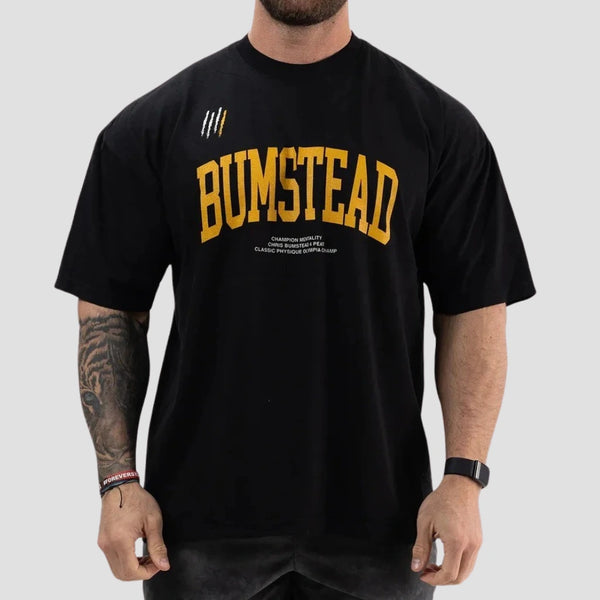 Homem vestindo a camiseta oversized preta da coleção CBUM da Iron Club, mostrando a estampa frontal amarela 'Bumstead'.