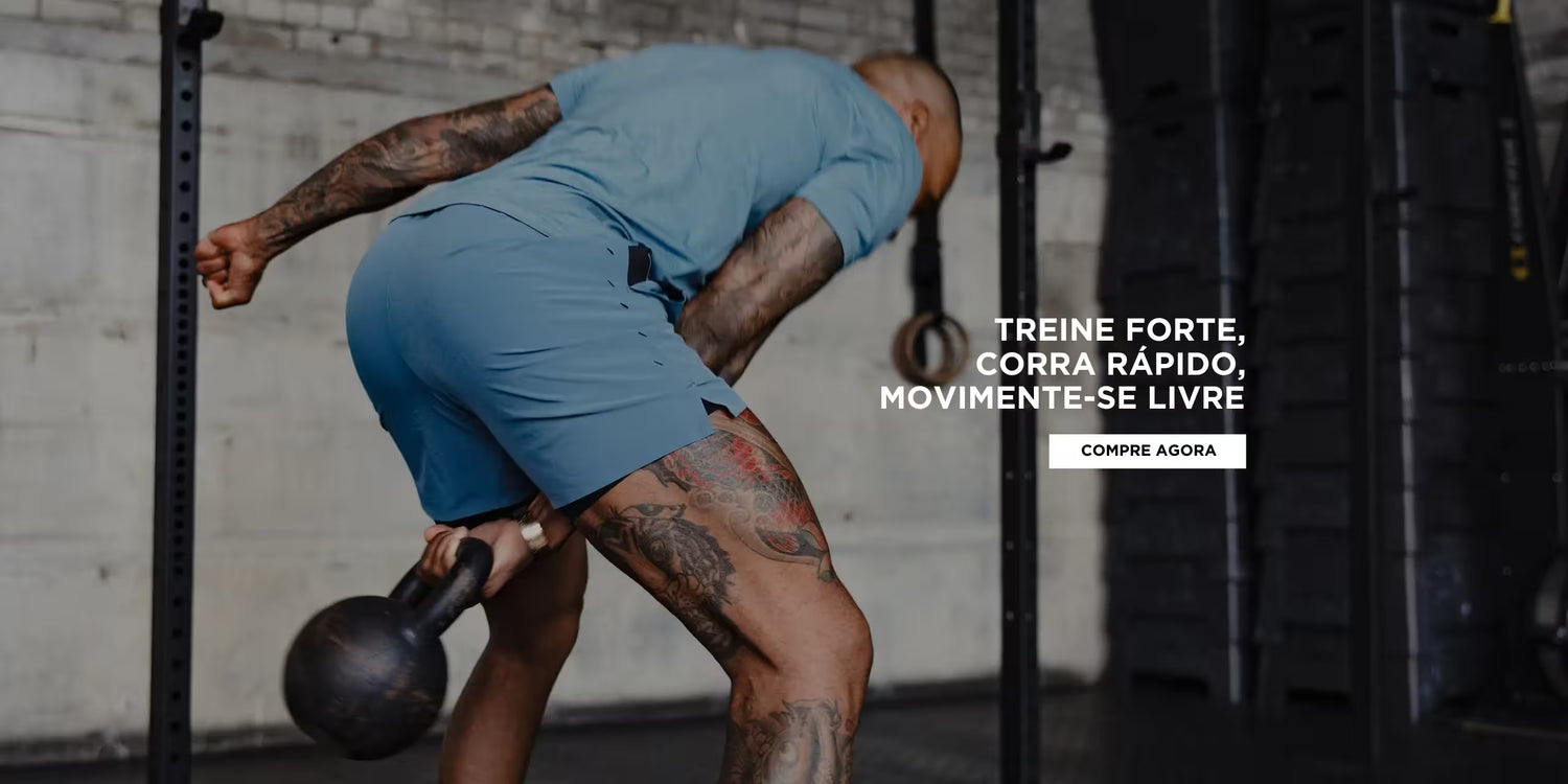 Atleta com shorts de treino azul da IronClub realizando exercício funcional com kettlebell em academia industrial, foco na peça e performance.