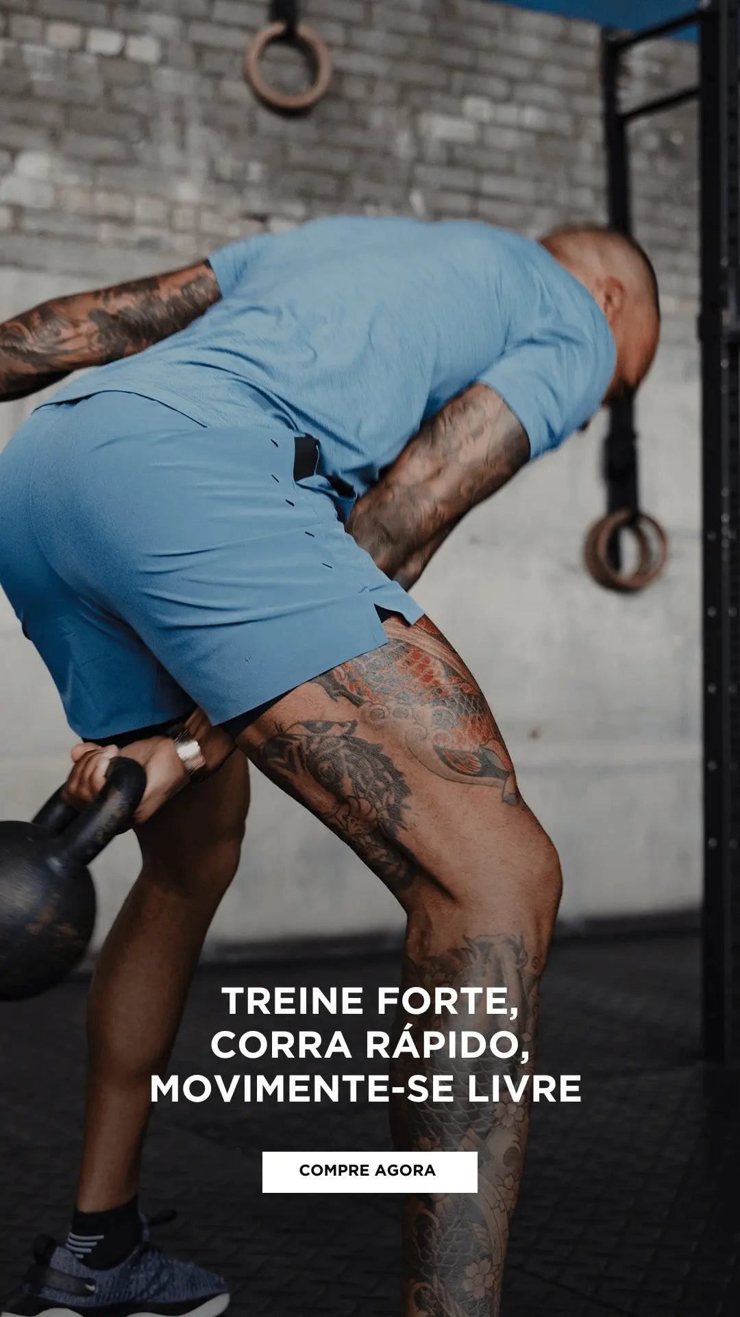 Atleta com shorts de treino azul da IronClub realizando exercício funcional com kettlebell em academia industrial, foco na peça e performance.