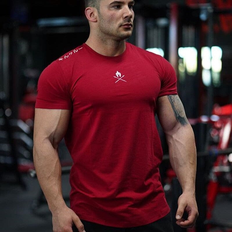 Close-up do caimento slim fit da camiseta Spartan vermelha no corpo de um atleta, destacando o peito e os braços.